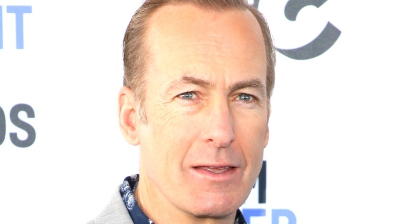 Bob Odenkirk smiles in ront of a white background
