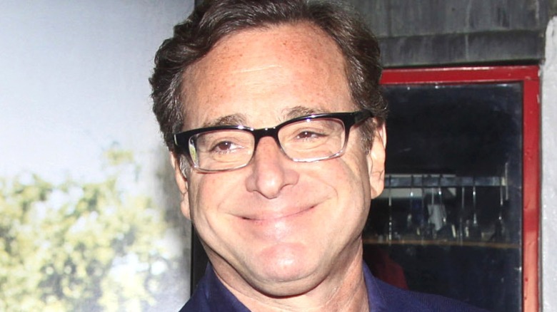 Bob Saget smiling with black glasses