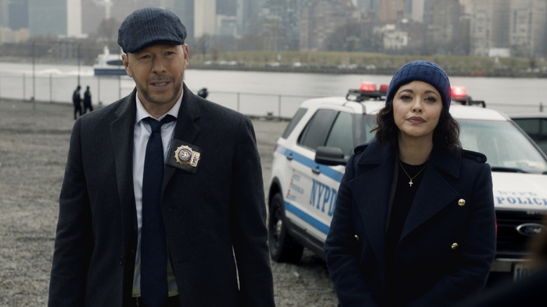 Danny Reagan and Maria Baez next to a cop car 