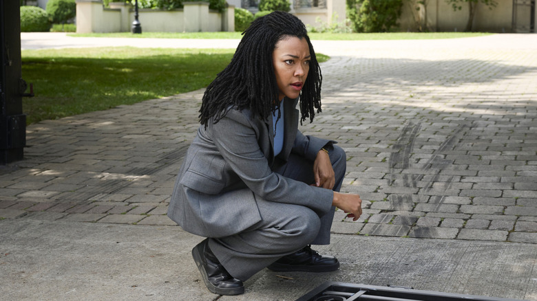 Lena squats next to a grate in "Boston Blue" (2025)