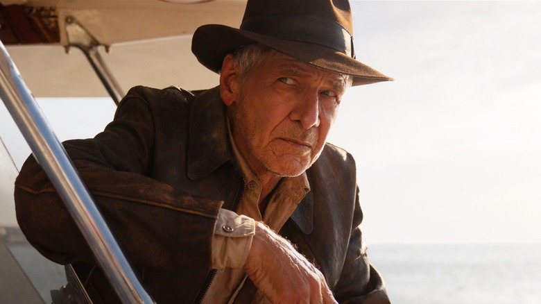 Indiana Jones leans next to a plane