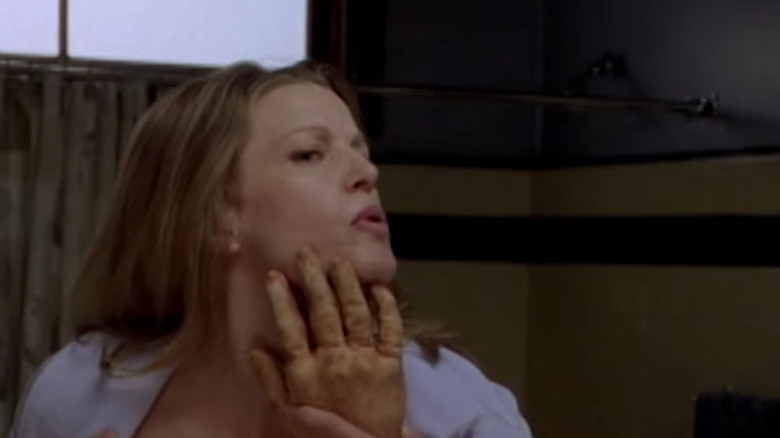 Anna Gunn looking in the mirror holding a prop hand