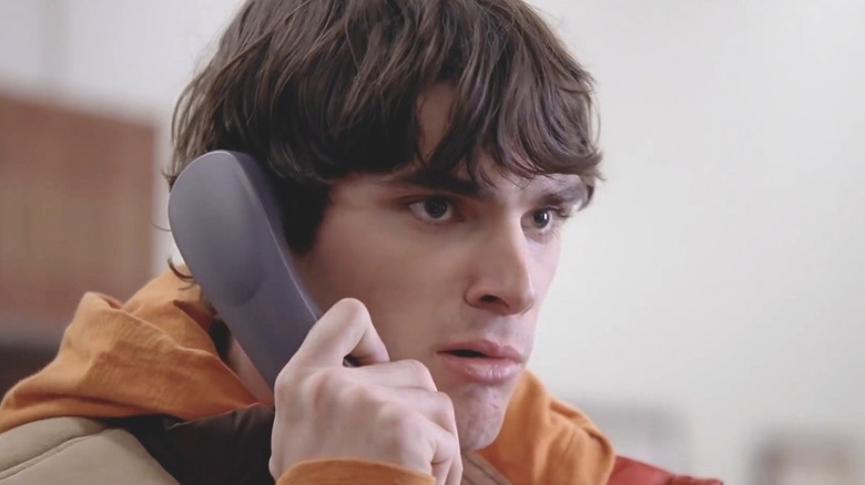 Flynn White Jr. holding phone to ear wearing orange hoodie