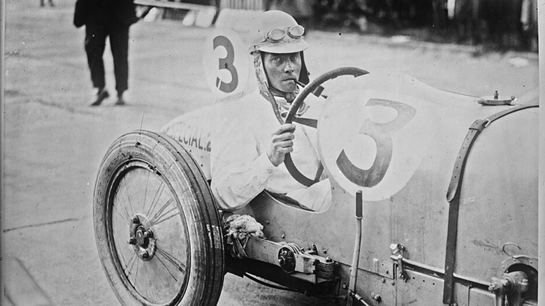 A black-and-white photo of the Earl of Cottenham, Mark Pepys, behind the wheel of a race car in 1925