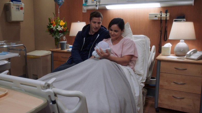 Jake and Amy sitting together in Amy's hospital bed and admiring their newborn son, Mac