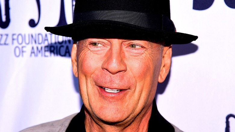 Bruce Willis smiling wearing a black hat
