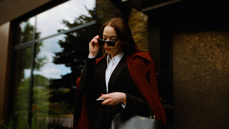Michelle lowers her sunglasses outside her house in "Bugonia" (2025)