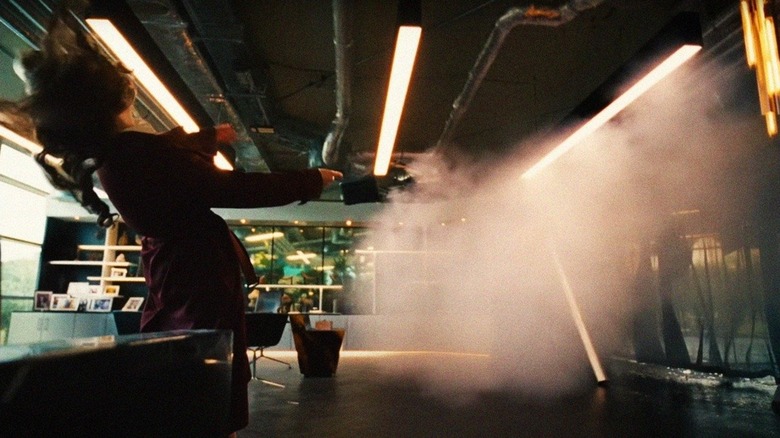 Michelle is blown backwards by an explosion in her office in "Bugonia" (2025)