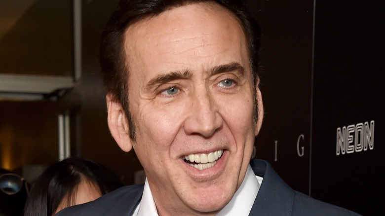 Nicolas Cage smiling and wearing gray suit