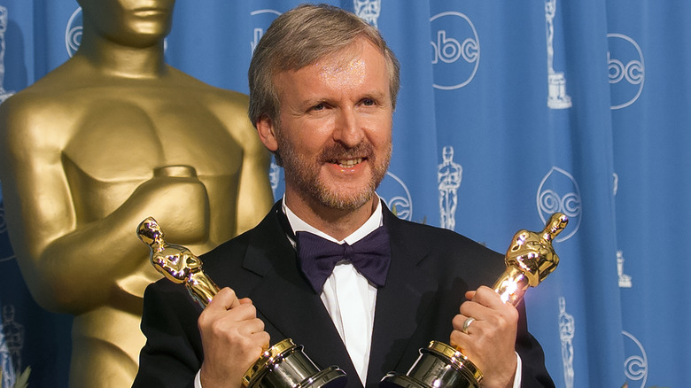 James Cameron holding two Oscars