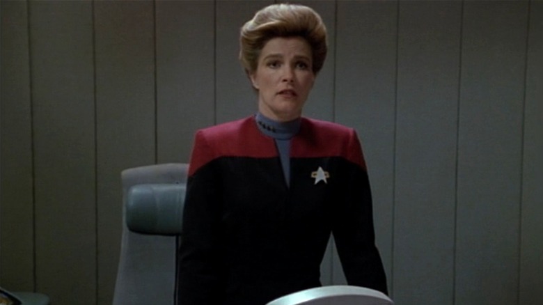 Captain Janeway standing attentively at desk