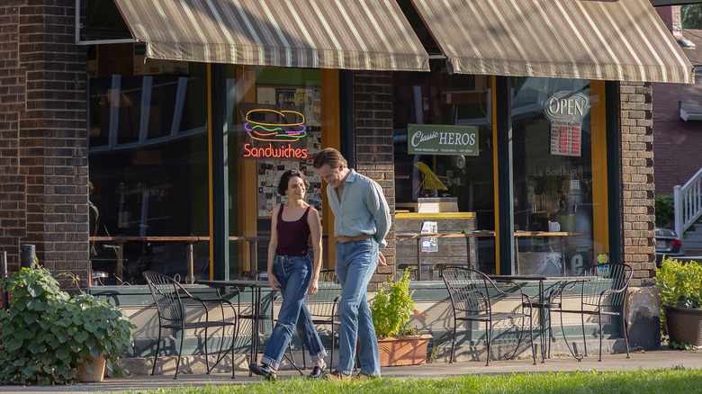 Rebecca and Noah walking past a sandwich shop in 