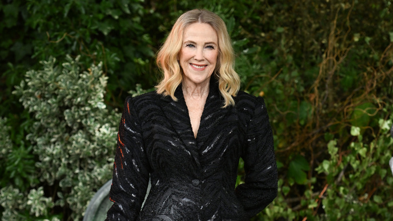 Catherine O'Hara in a black jacket in front of trees in Schitt's Creek