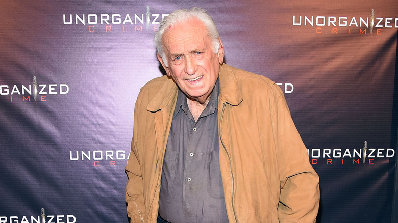 Carmine Caridi in a tan jacket