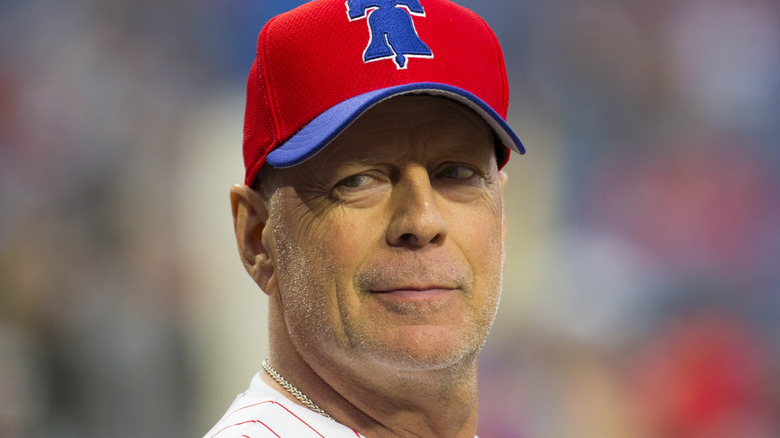 Bruce Willis smirking in a baseball cap at the Milwaukee Brewers and Philadelphia Phillies game (2019)