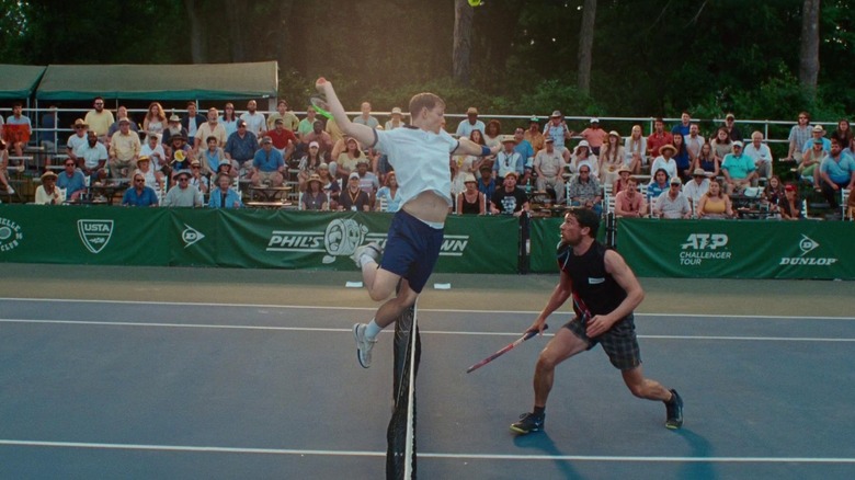 Art jumping over the net and hitting the tennis ball as Patrick prepares to respond in "Challengers"