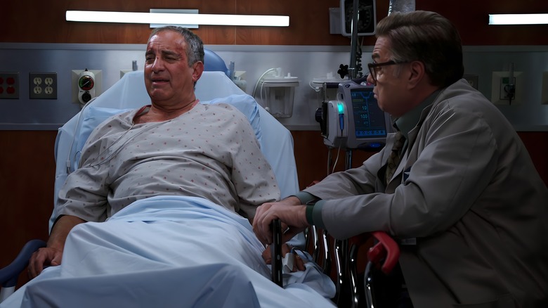 Dr. Charles sitting next to Fred in a hospital bed