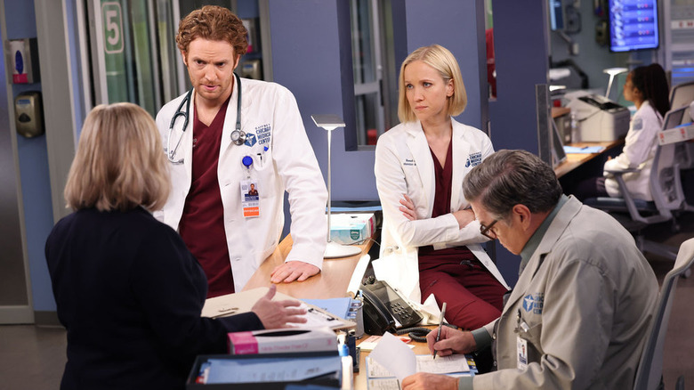 Chicago Med cast gathered around desk 