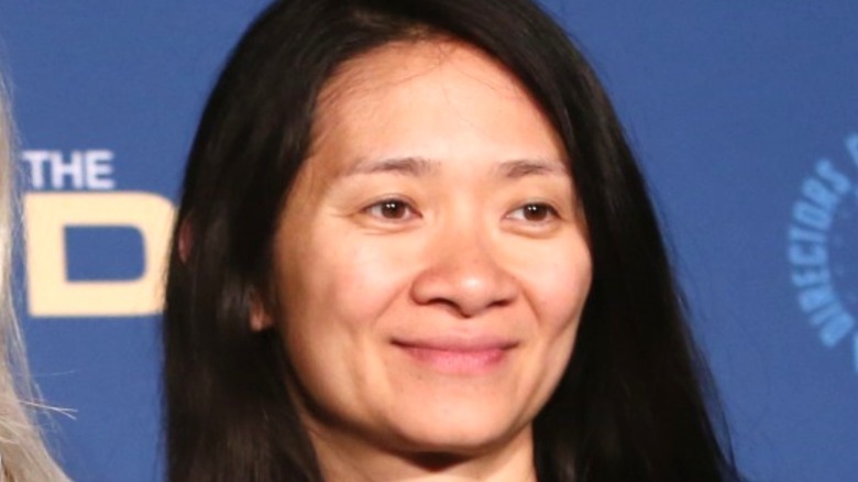 Eternals director Chloe Zhao in front of blue backdrop