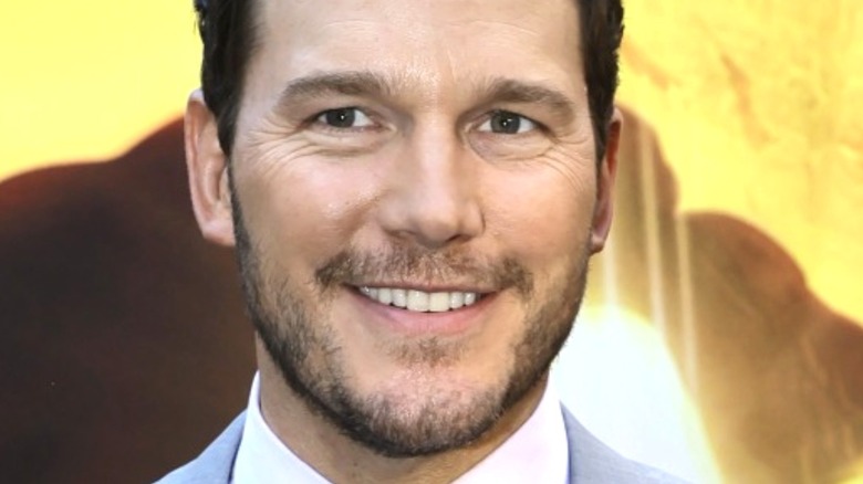 Chris Pratt smiling in front of a yellow background