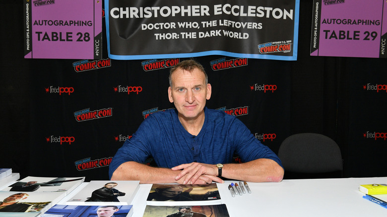 Eccleston sits at a table