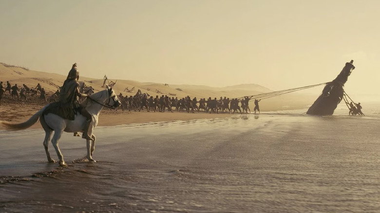 A man on a horse watching an army lift a structure in The Odyssey