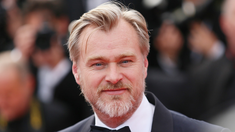 Christopher Nolan smiling in a suit