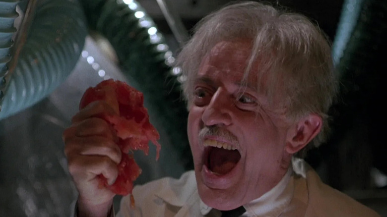 Professor Gangreen holding a squished tomato in "Return of the Killer Tomatoes" (1988)