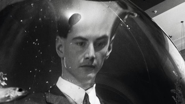 Johnny staring at his warped reflection in a curved surface in Johnny Mnemonic (1995)
