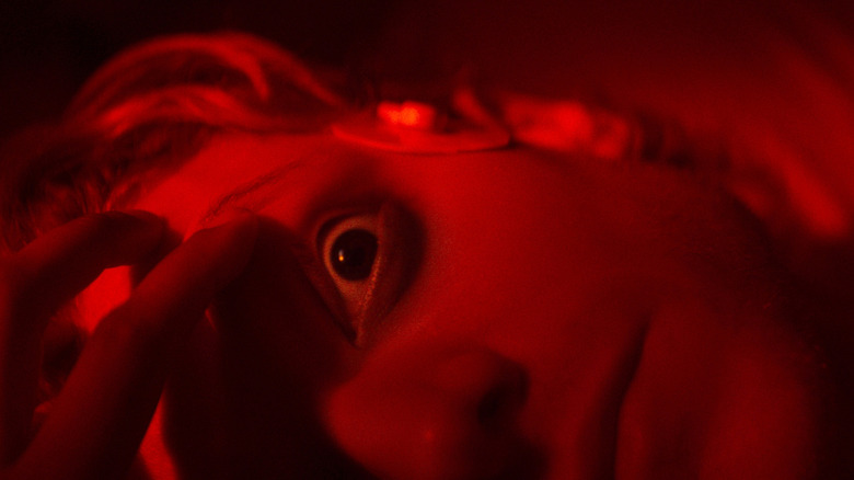 Matt Hagen under harsh red light, camera zoomed in close on his face, holding one eyelid open, in Clayface (2026)