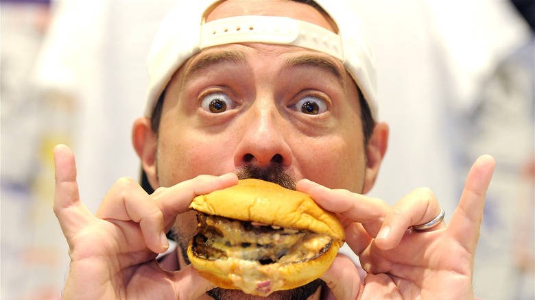 Kevin Smith posing with a cheeseburger