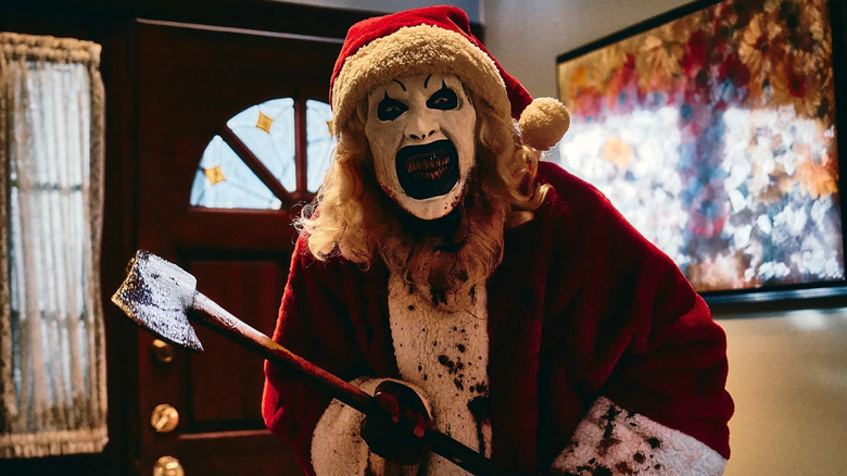 Art the clown mugging while dressed as Santa Claus with an axe in "Terrifier 3" (2024)