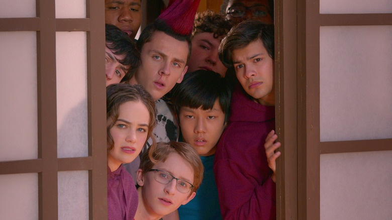 Mary Mouser, Jacob Bertram, Xolo Maridueña and castmates peering around the corner