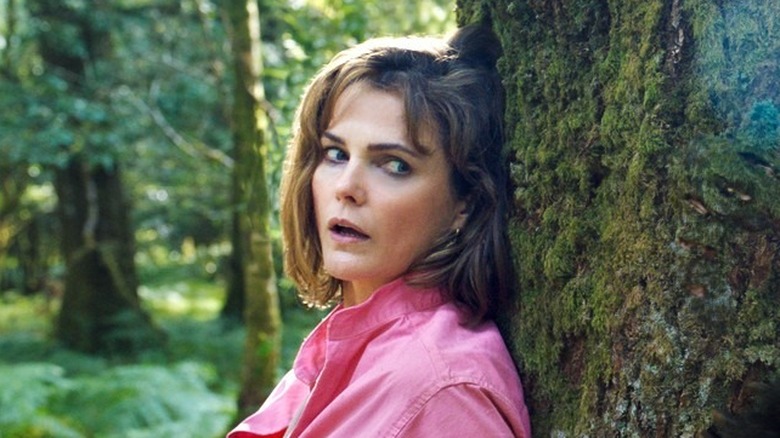 Keri Russell hiding behind tree in "Cocaine Bear"