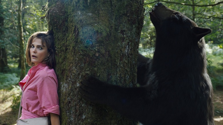 Keri Russel backed up against a tree with a bear on cocaine on the other side in Cocaine Bear