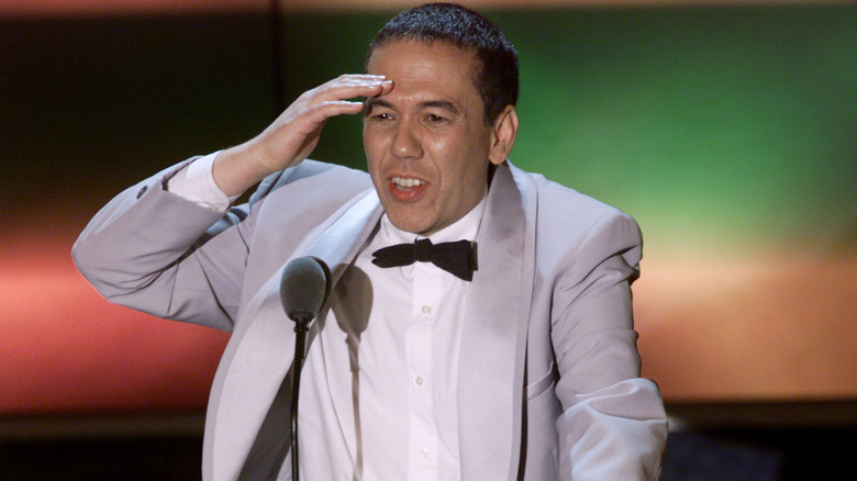 Gilbert Gottfried in a gray tux touching his head
