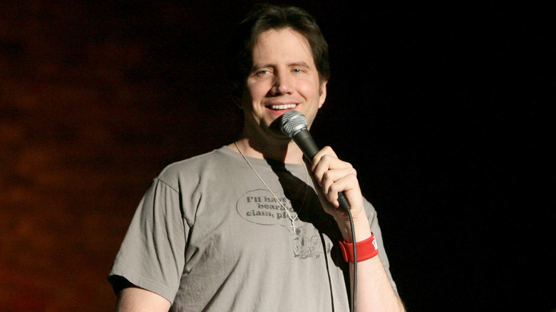 Jamie Kennedy with a gray T-shirt holding a microphone
