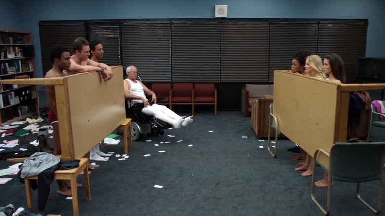 The study group standing semi-naked behind tables in "Cooperative Calligraphy" (2010)