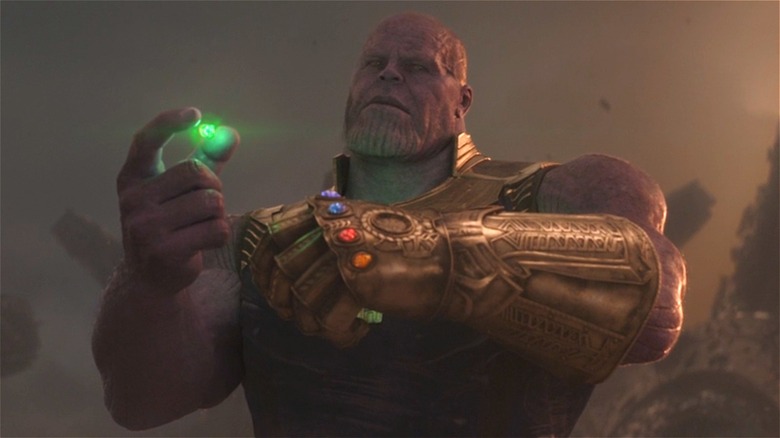Thanos putting the Time Stone in the Infinity Gauntlet on his hand 