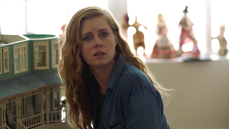 Camille crouches next to a dollhouse in "Sharp Objects" (2018)