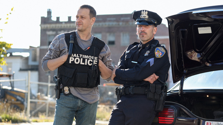 Daniel and Wayne standing by a car in "We Own This City" (2022)