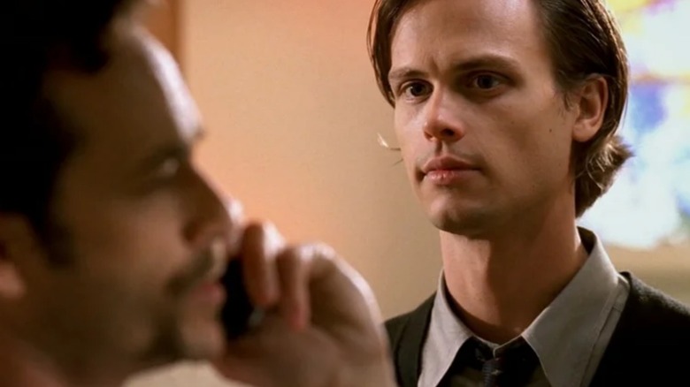 Spencer Reid looking over someone on a phone call