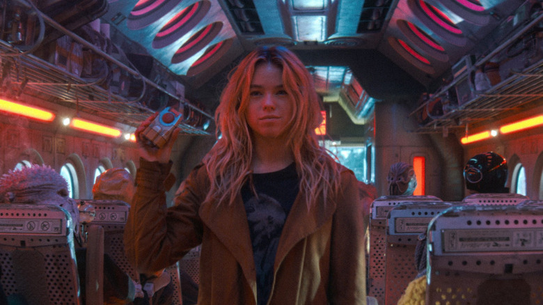 Kara Zor-El holding device and smirking in 