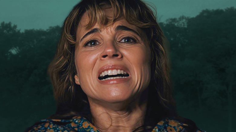 Pamela looking distraught in front of forest background