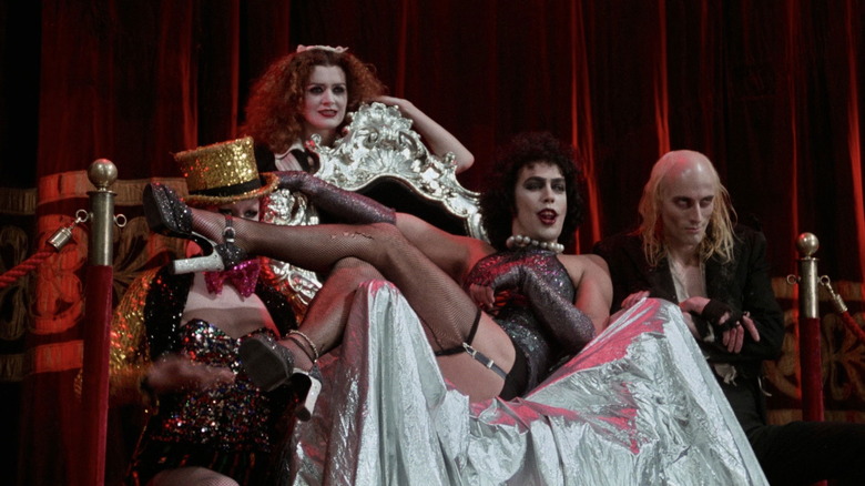 Frank leaning on a throne, surrounded by the other Transylvanians in The Rocky Horror Picture Show