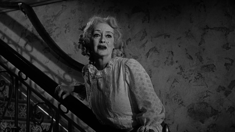 Jane holding the railing of a staircase in What Ever Happened to Baby Jane?