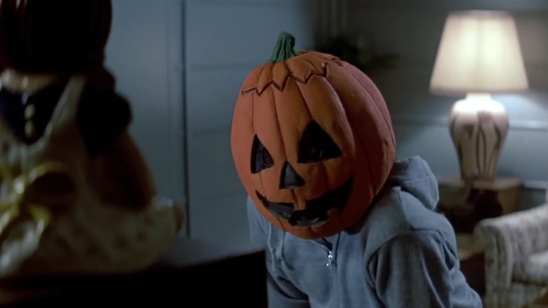 A kid in a blue hoodie wearing a pumpkin mask watching television in Halloween III: Season of the Witch