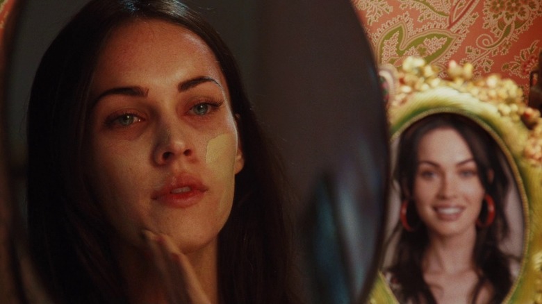 Jennifer Check applying foundation in the mirror next to a photograph in Jennifer's Body