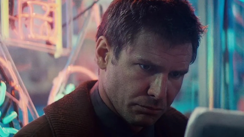 Deckard next to some neon signs in Blade Runner (1982)