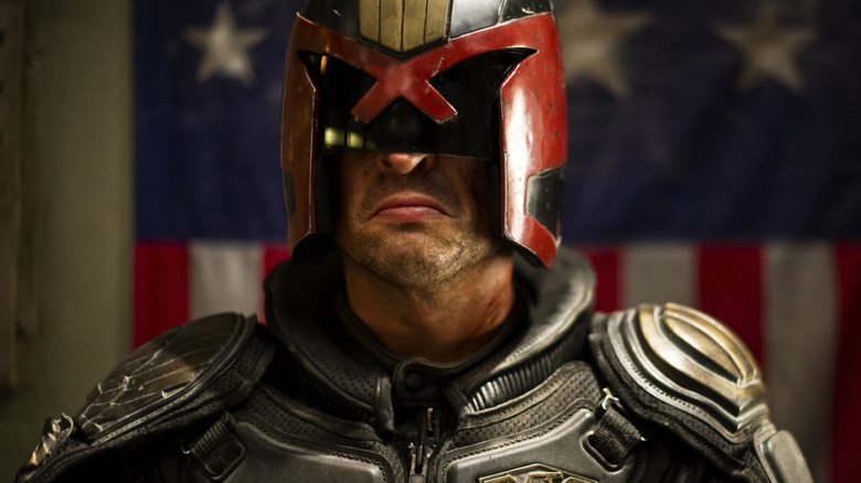 Judge Dredd scowling before a red, white and blue flag in Dredd (2012)